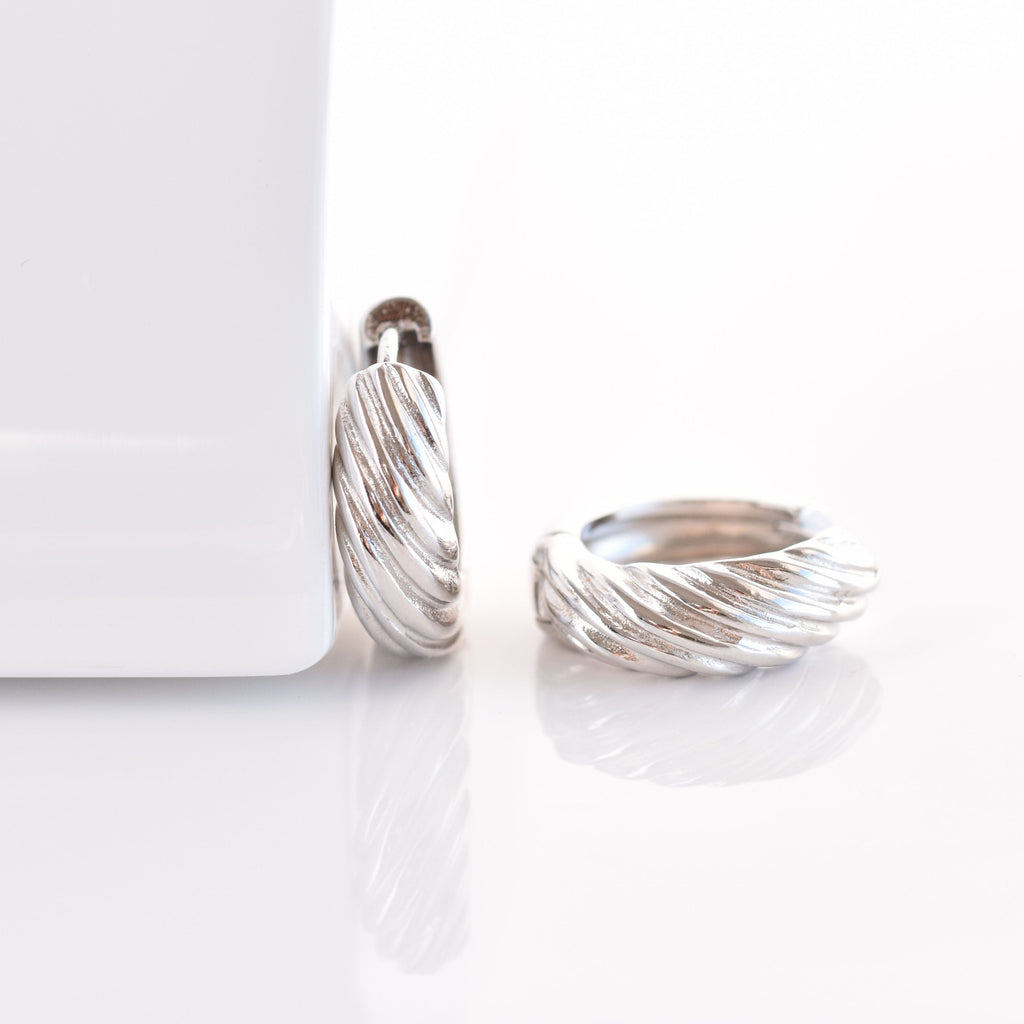 Pair of silver hoop earrings on a white surface