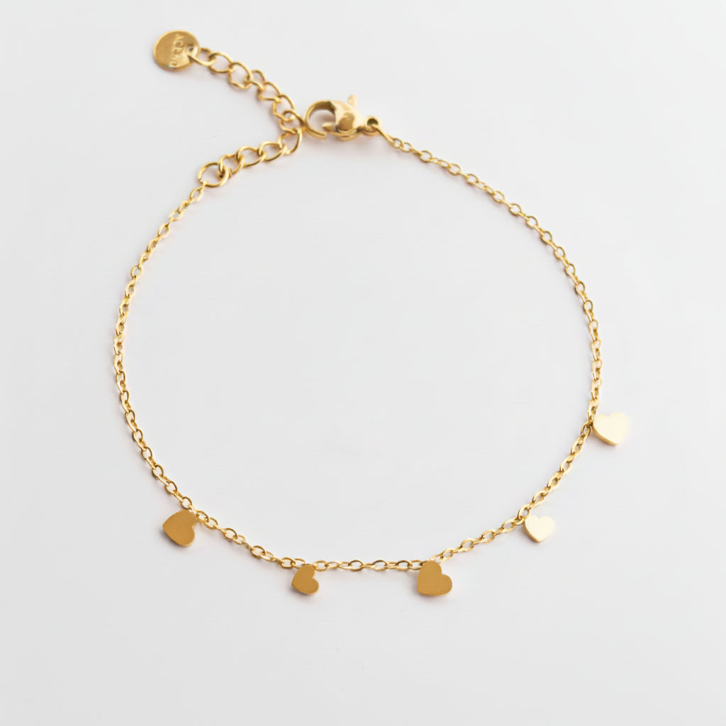 gold dainty stainless steal chain bracelet with five small flat heart charms on a white studio background.