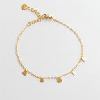 gold dainty stainless steal chain bracelet with five small flat heart charms on a white studio background.