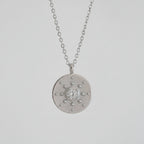 Silver necklace with a round pendant on a white background